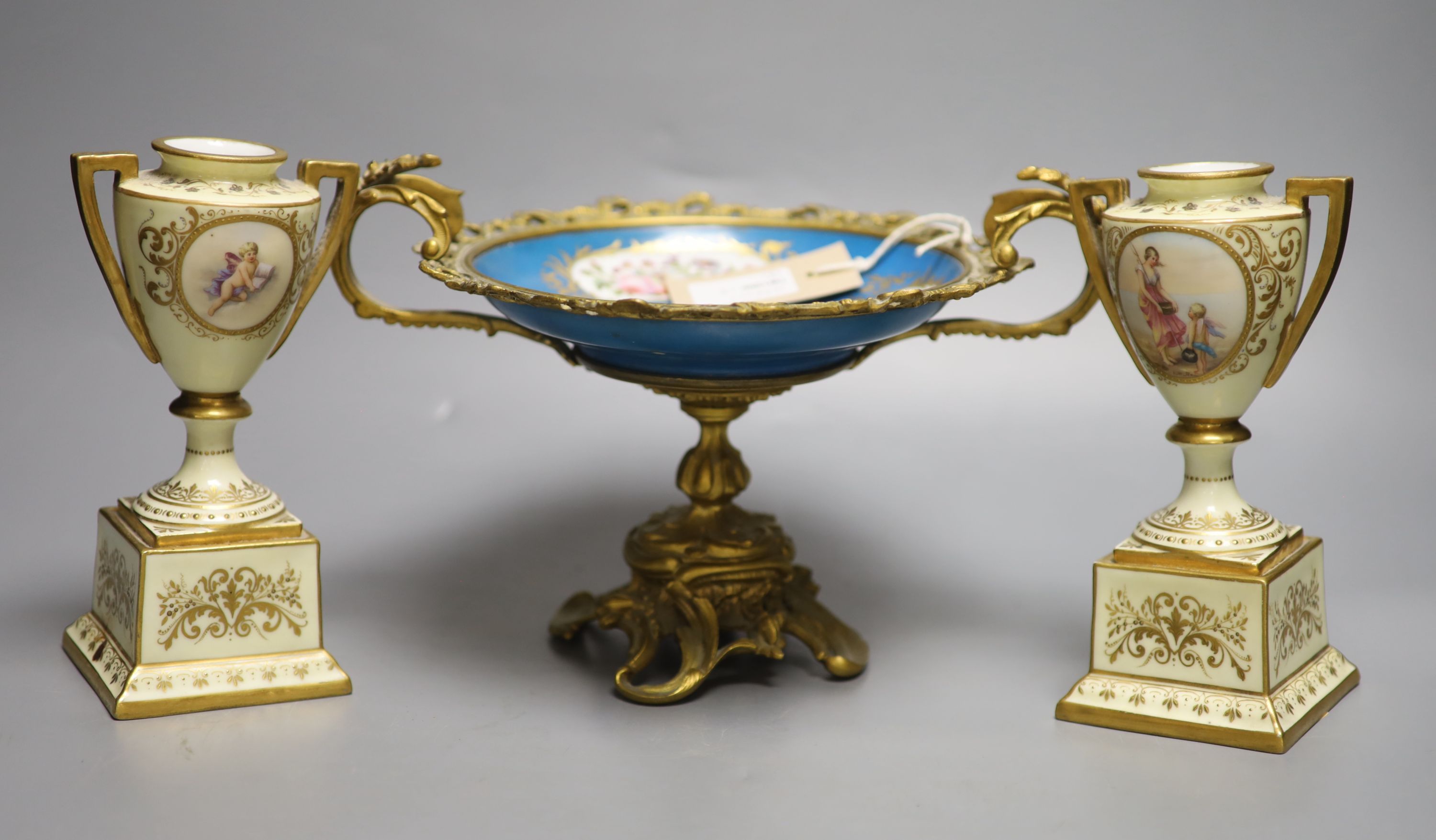 A pair of Vienna style porcelain urns, height 18cm and a Sevres style ormolu-mounted tazza